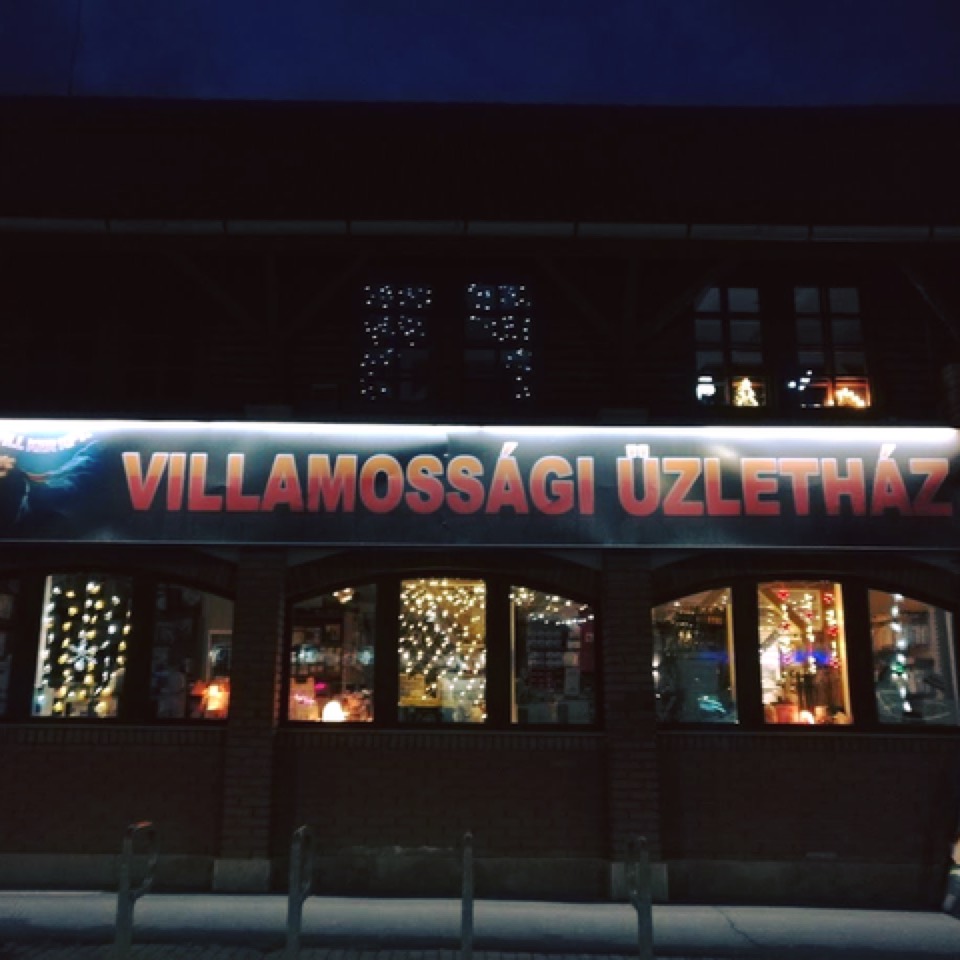 A Rockvillker üzletház homlokzata este, kivilágított kirakatokkal és fényfüzérekkel.